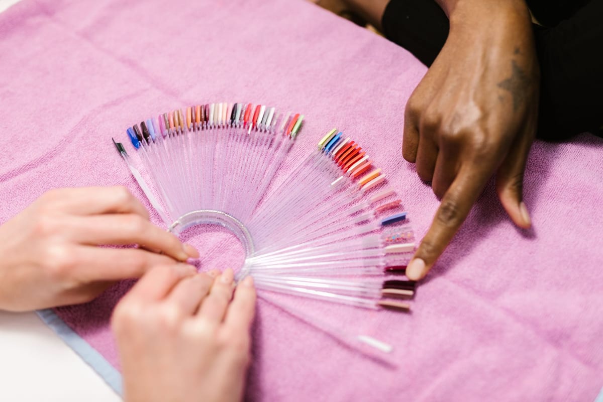 Hand pointing to a wall of nail polish colours