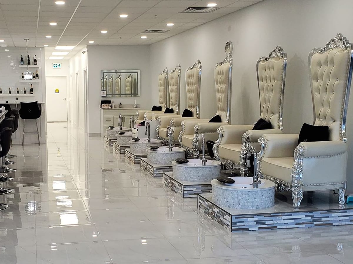 Row of tufted king throne pedicure chairs and a champagne bar inside Royal Nail Bar in Kitchener